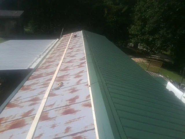 Old rusted panels beside newly installed green metal roofing — Wind Damage Roof Repair by Roofing Brothers in Elliottsburg