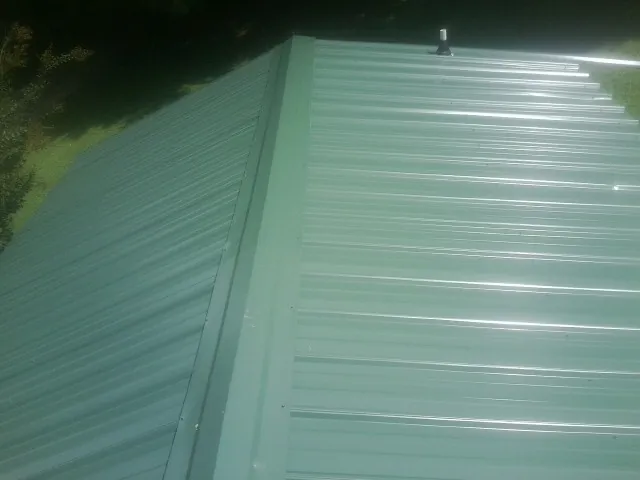 New green metal panels meeting at the ridge of a roof — Flat Roof Repair work by our crew in Elliottsburg