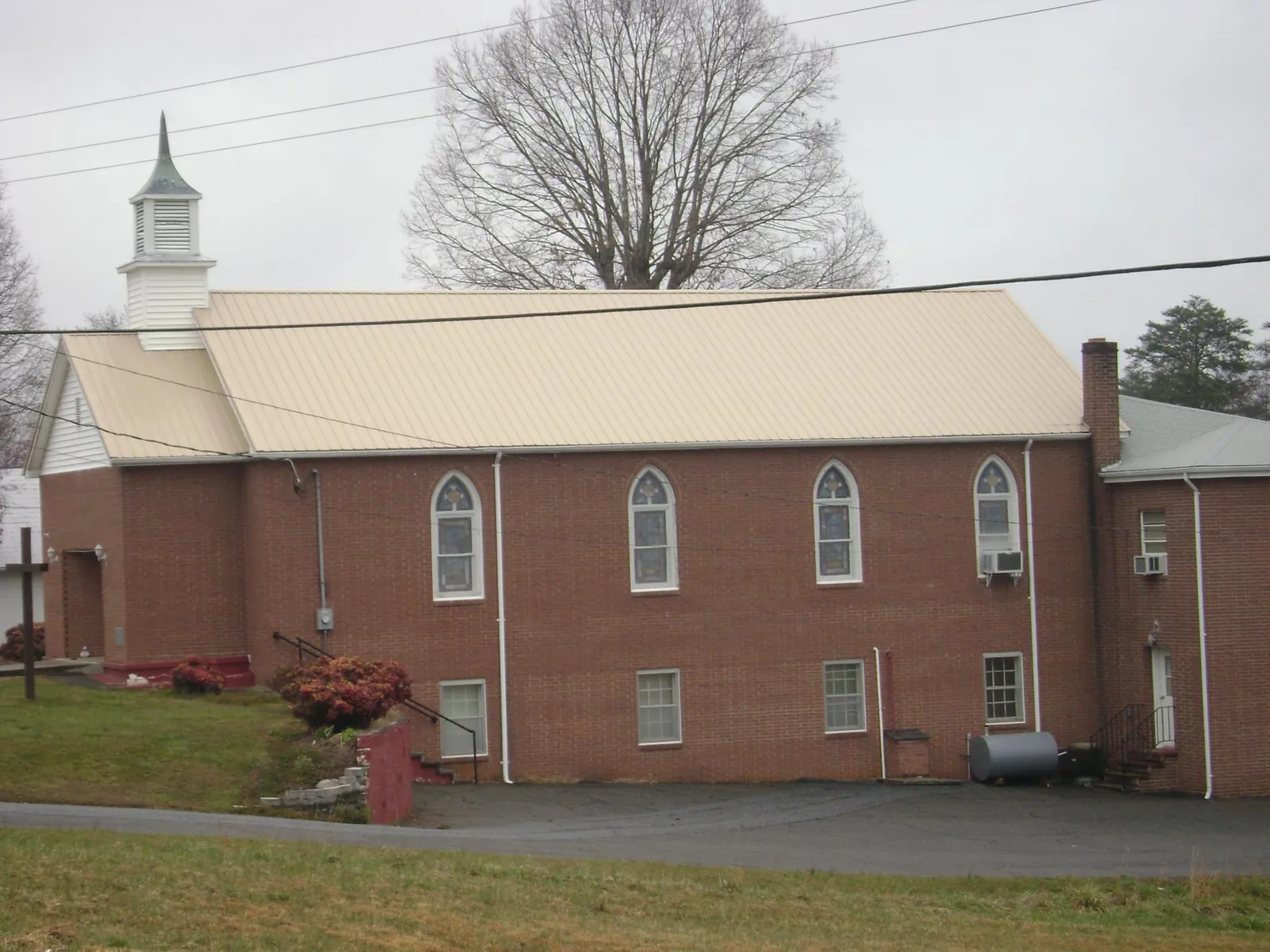 New tan metal roof on a brick church with a white steeple in Elliottsburg