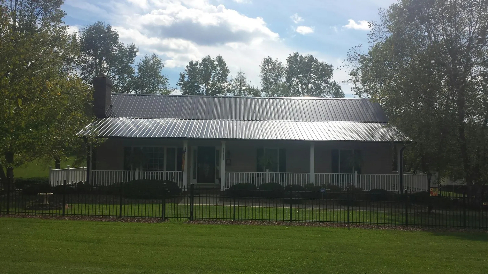 Gray metal roof on a brick ranch with a full width front porch — Gutter Guard Installation work by our crew in Elliottsburg