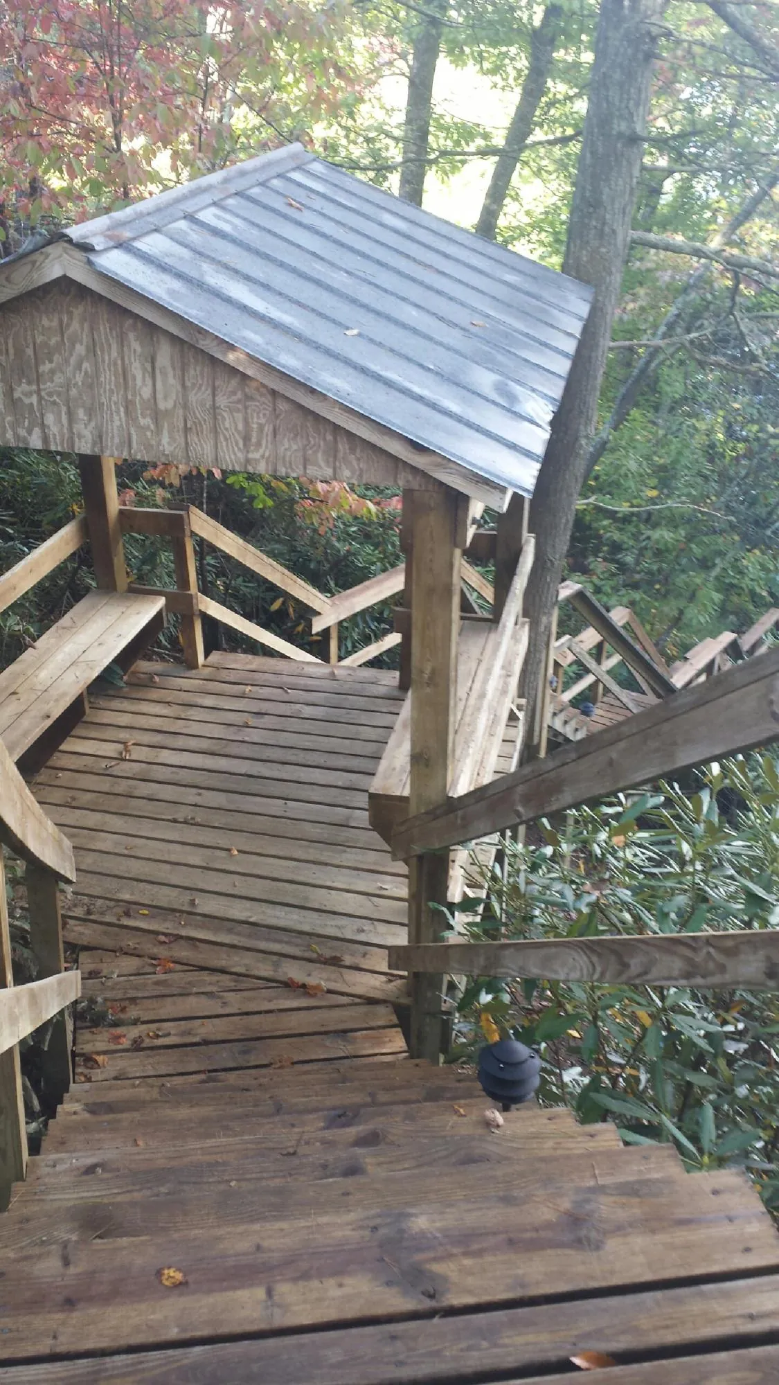 Metal roofed shelter over wooden steps on a wooded walkway — Skylight Repair & Installation work by our crew in Elliottsburg