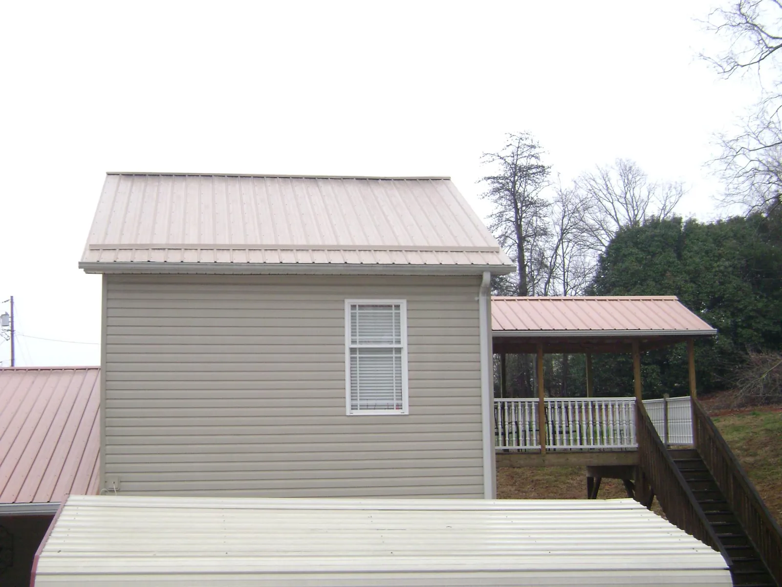 Tan metal roofs on a two story addition and attached porch, from a Roof Replacement job in Elliottsburg